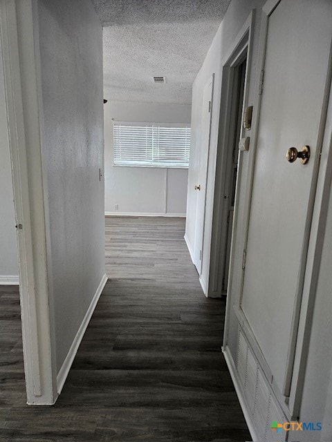 hallway with dark wood-type flooring and a textured ceiling