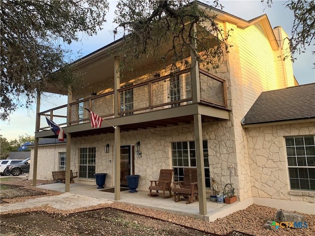 448 Summer Glen Ln, New Braunfels, TX 78132 - back of property featuring a balcony, stone siding, a patio, and a shingled roof