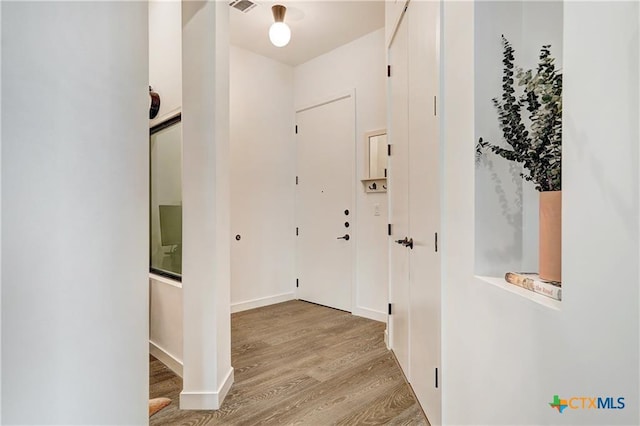 hall featuring light wood finished floors, visible vents, and baseboards