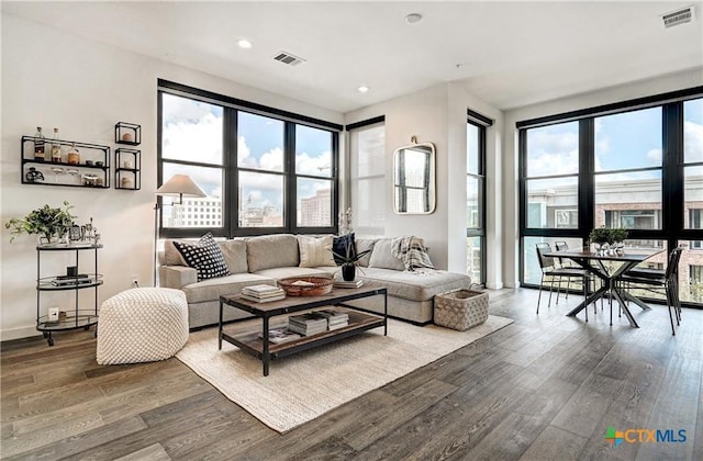 living room featuring a healthy amount of sunlight, visible vents, and wood finished floors