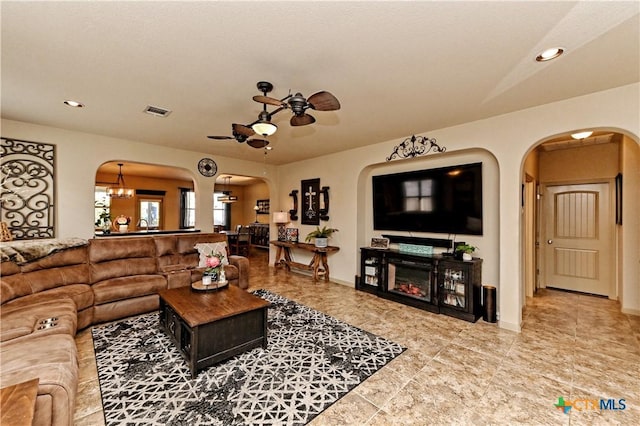 living room featuring ceiling fan with notable chandelier