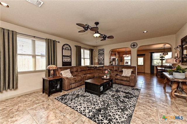 living room with ceiling fan with notable chandelier and a healthy amount of sunlight