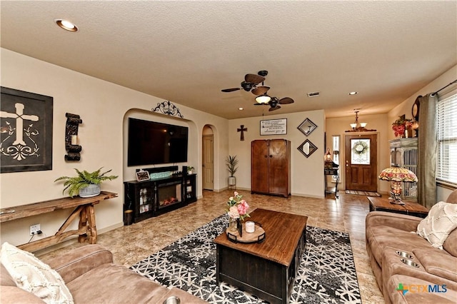 living room with a textured ceiling and ceiling fan with notable chandelier