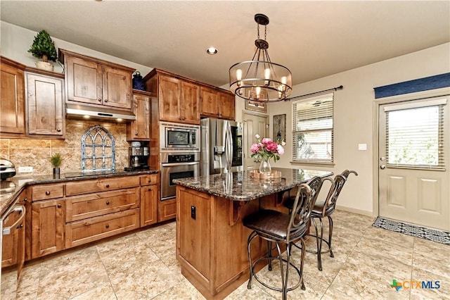 kitchen featuring backsplash, a center island, an inviting chandelier, hanging light fixtures, and stainless steel appliances