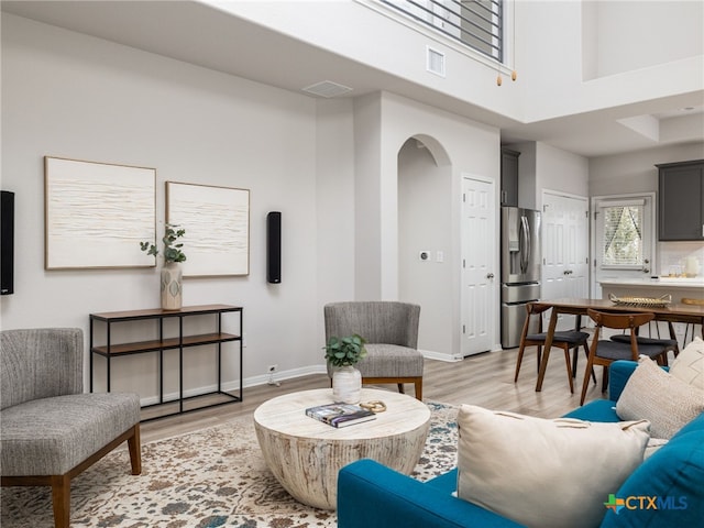 living room with light wood-style flooring, visible vents, and arched walkways