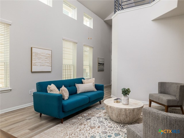 living room featuring wood finished floors, a towering ceiling, and baseboards