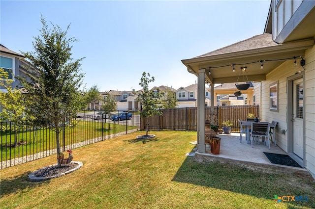 view of yard with a patio, a fenced backyard, and a residential view