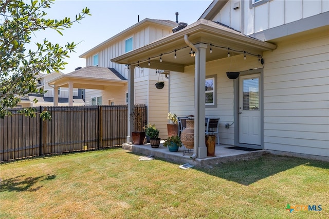 exterior space featuring a patio area, a lawn, fence, and board and batten siding