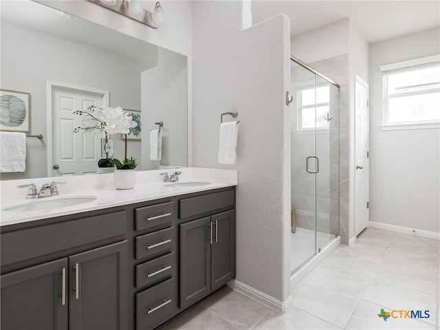 bathroom featuring a stall shower, tile patterned flooring, a sink, and double vanity