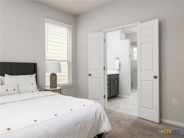 bedroom featuring ensuite bathroom, baseboards, and light colored carpet