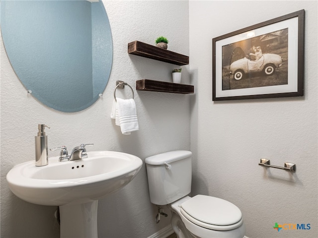 half bath with a textured wall and toilet