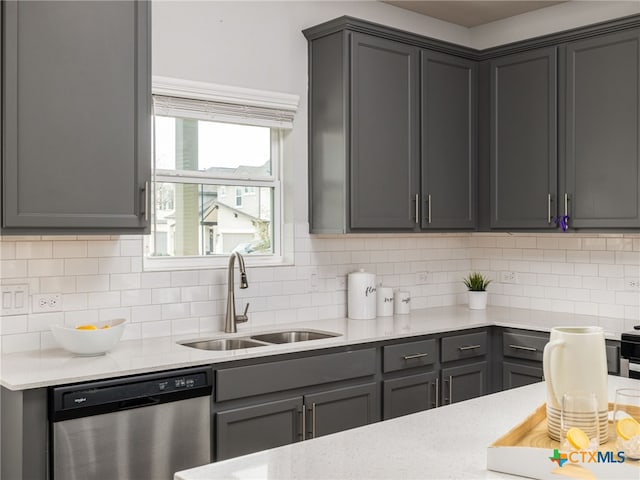 kitchen featuring gray cabinetry, dishwasher, backsplash, and a sink