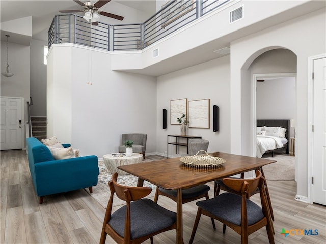 dining space featuring light wood-style flooring, a high ceiling, and visible vents