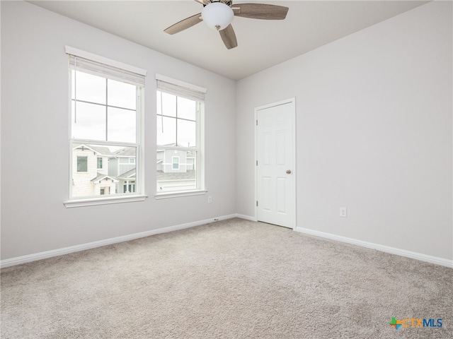 spare room featuring baseboards, a ceiling fan, and light colored carpet