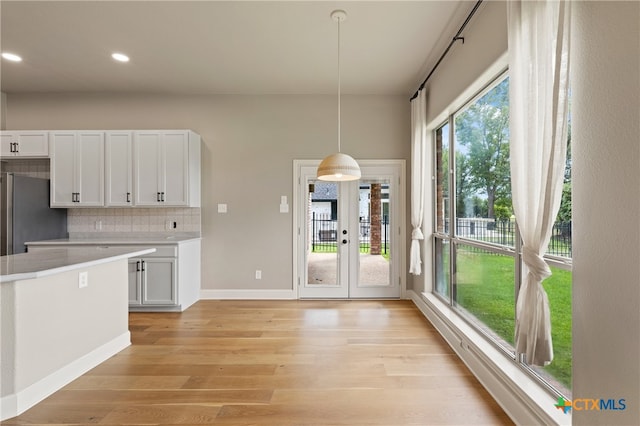 kitchen with light hardwood / wood-style floors, white cabinetry, decorative light fixtures, and tasteful backsplash