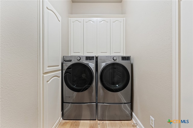 laundry area featuring separate washer and dryer, light hardwood / wood-style flooring, and cabinets