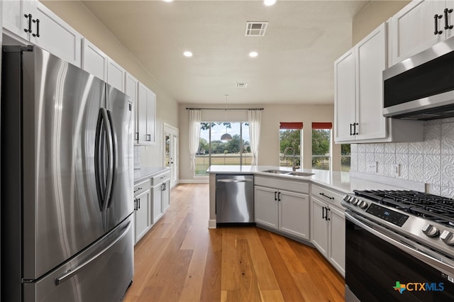 kitchen featuring light hardwood / wood-style floors, white cabinetry, sink, appliances with stainless steel finishes, and decorative backsplash