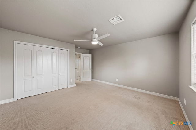 unfurnished bedroom with a closet, light carpet, and ceiling fan