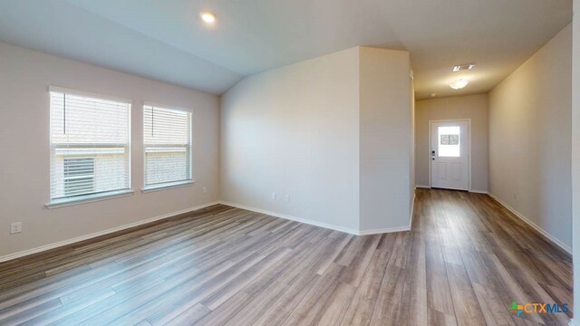 spare room with wood-type flooring and vaulted ceiling