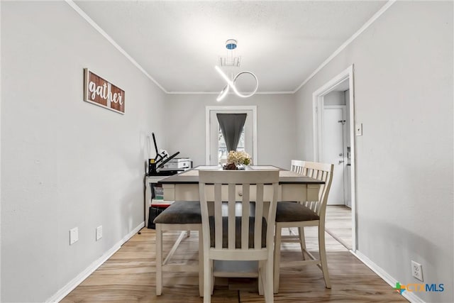 dining space featuring ornamental molding and light hardwood / wood-style flooring