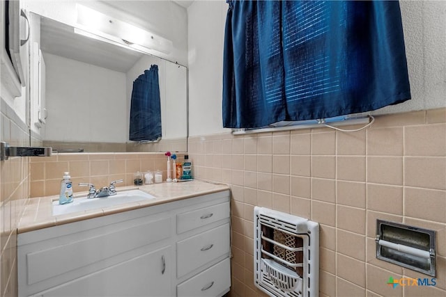 bathroom with vanity, heating unit, and tile walls