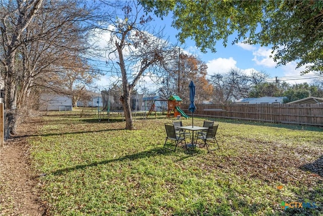 view of yard with a trampoline, a playground, and a fenced backyard