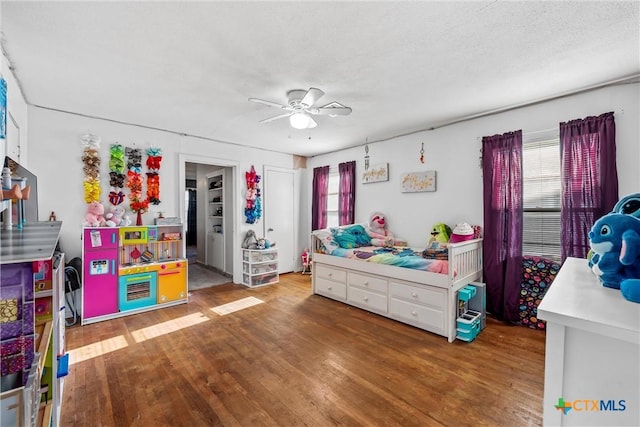 bedroom with ceiling fan, wood-type flooring, a textured ceiling, and multiple windows