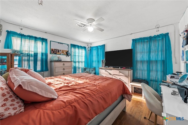 bedroom with hardwood / wood-style floors, ceiling fan, and a textured ceiling