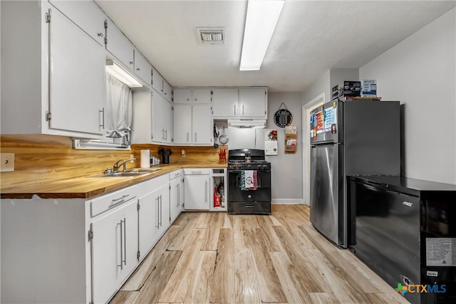 kitchen with refrigerator, white cabinetry, sink, and black range with gas cooktop