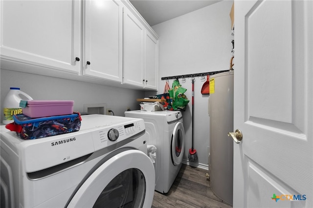 clothes washing area featuring electric water heater, hardwood / wood-style flooring, cabinets, and washing machine and dryer