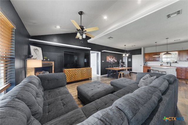 living room with light wood-type flooring, vaulted ceiling, and ceiling fan