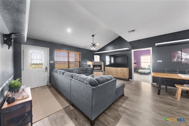 living room featuring wood-type flooring, ceiling fan, and vaulted ceiling