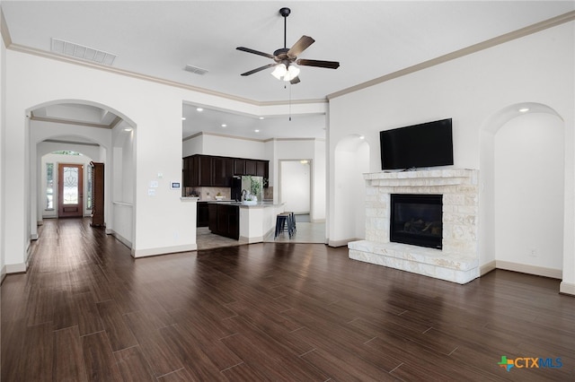 8235 Shining Elk, Garden Ridge, TX 78266 - unfurnished living room featuring ceiling fan, dark wood-type flooring, crown molding, a fireplace, and arched walkways