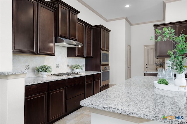 8235 Shining Elk, Garden Ridge, TX 78266 - kitchen with appliances with stainless steel finishes, backsplash, under cabinet range hood, dark brown cabinetry, and light stone counters