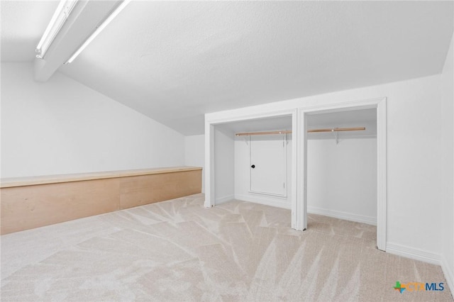 additional living space with vaulted ceiling, a textured ceiling, and light carpet