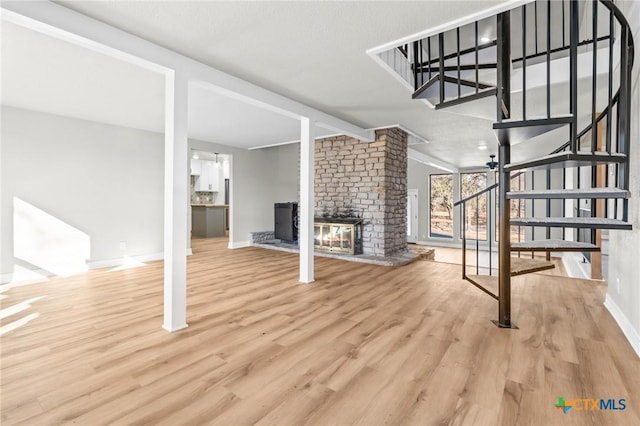 unfurnished living room with light wood-type flooring and a brick fireplace