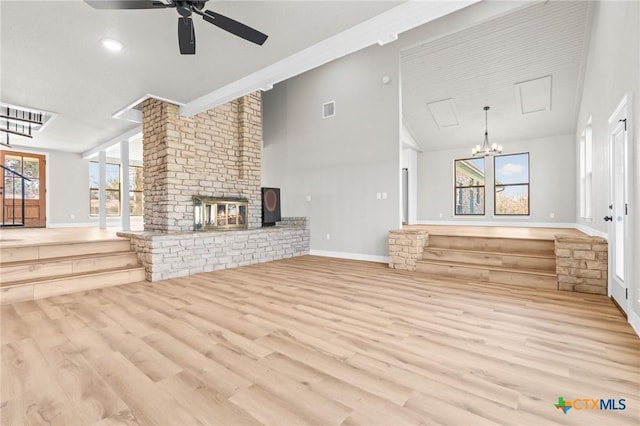 unfurnished living room featuring light wood-type flooring, a brick fireplace, plenty of natural light, and ceiling fan with notable chandelier