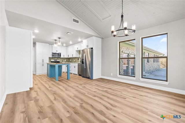 kitchen with a breakfast bar area, appliances with stainless steel finishes, a kitchen island, and decorative light fixtures