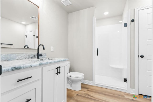 bathroom featuring toilet, a shower with shower door, hardwood / wood-style flooring, and vanity