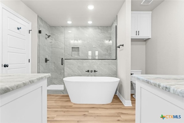 full bathroom featuring toilet, vanity, shower with separate bathtub, and hardwood / wood-style floors