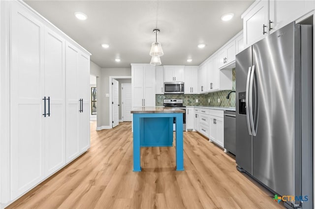 kitchen featuring a kitchen bar, white cabinets, hanging light fixtures, and appliances with stainless steel finishes