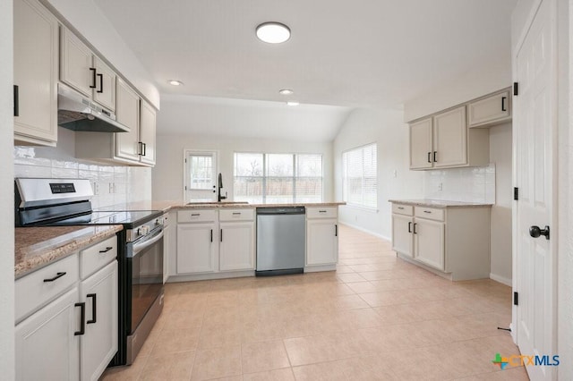 kitchen featuring vaulted ceiling, kitchen peninsula, sink, light tile patterned flooring, and stainless steel appliances