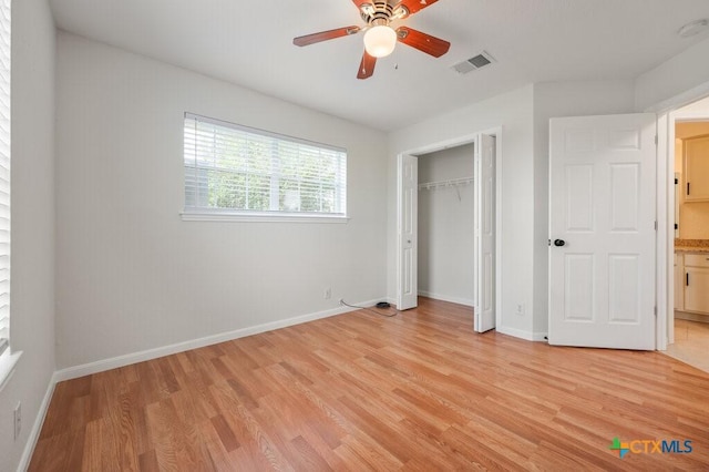 unfurnished bedroom with ceiling fan, light wood-type flooring, and a closet