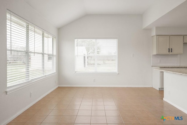 unfurnished dining area with light tile patterned floors and lofted ceiling