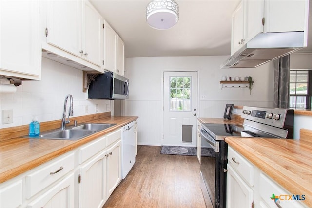 2210 Buckskin Trl, Temple, TX 76502 - kitchen featuring appliances with stainless steel finishes, a sink, healthy amount of natural light, light wood-style flooring, and a wainscoted wall