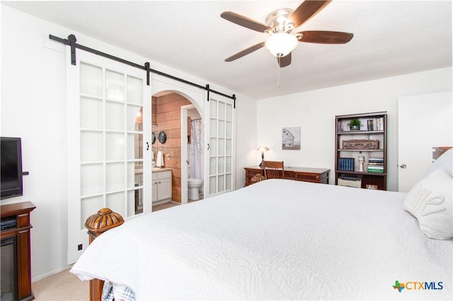 2210 Buckskin Trl, Temple, TX 76502 - carpeted bedroom with a barn door, arched walkways, a ceiling fan, and connected bathroom