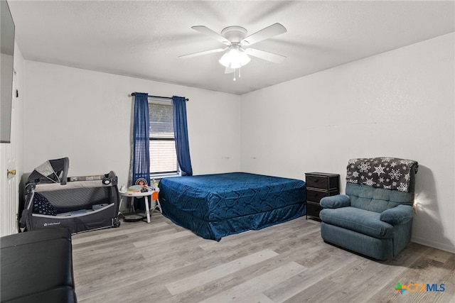 bedroom with a textured ceiling, light hardwood / wood-style floors, and ceiling fan