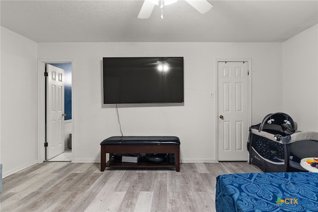 bedroom with a textured ceiling, light wood-type flooring, ceiling fan, and connected bathroom