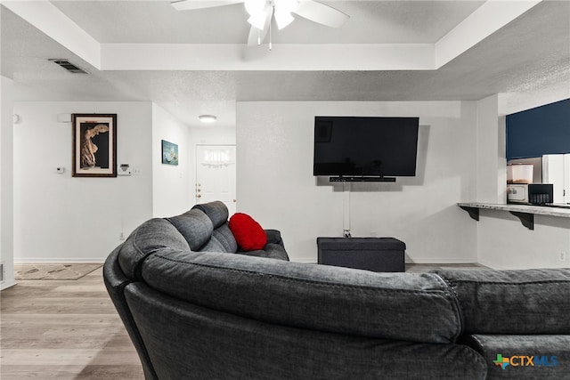 living room featuring a textured ceiling, ceiling fan, and light hardwood / wood-style flooring