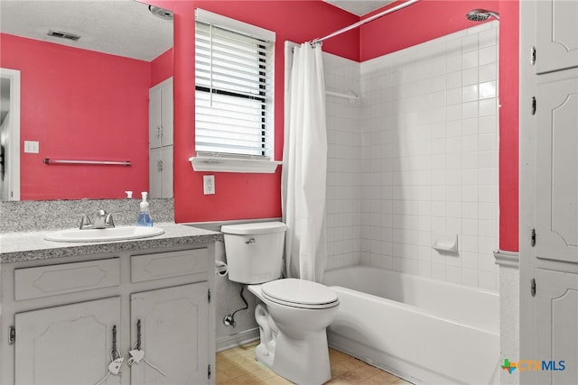 full bathroom featuring toilet, shower / bath combo, vanity, and a textured ceiling